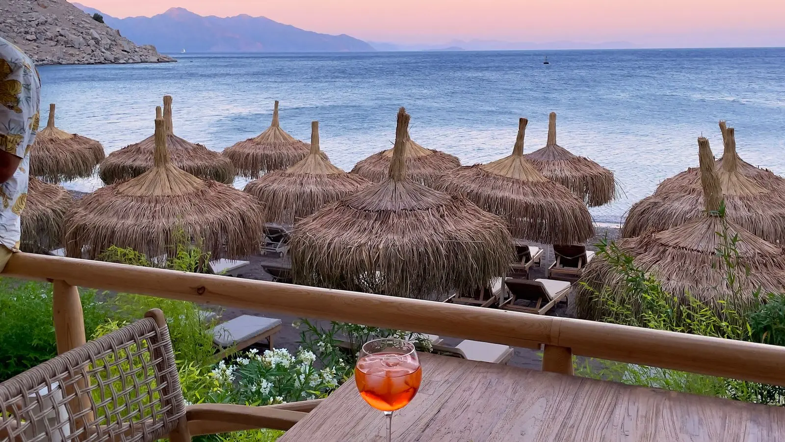 Zalazak sunca nad morem sa terase beach bara, planine u daljini